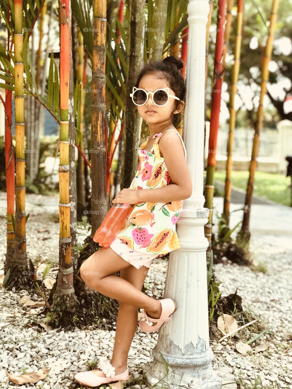 A cute girl lean over the lamp pole by holding cool drink in her hand and she is in summer outfits and cooling glasses to eyes 😍