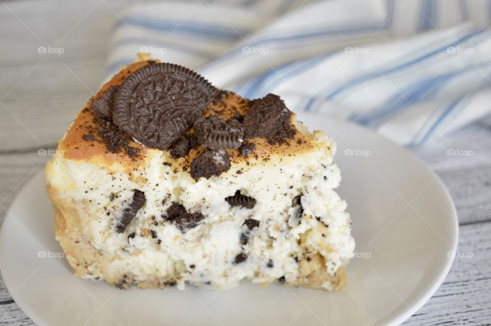 Oreo cookie cheesecake on a white plate with a blue and white towel in the background
