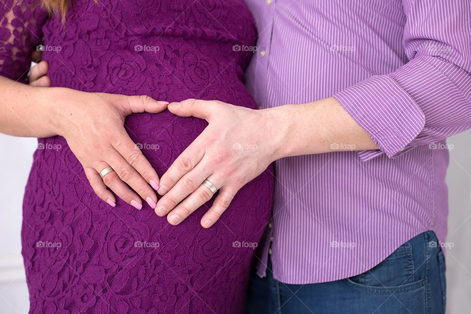 Man and woman doing heart on her pregnant belly 