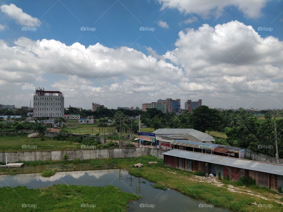 Water..... green grasses..... clouds...concrete buildings.....