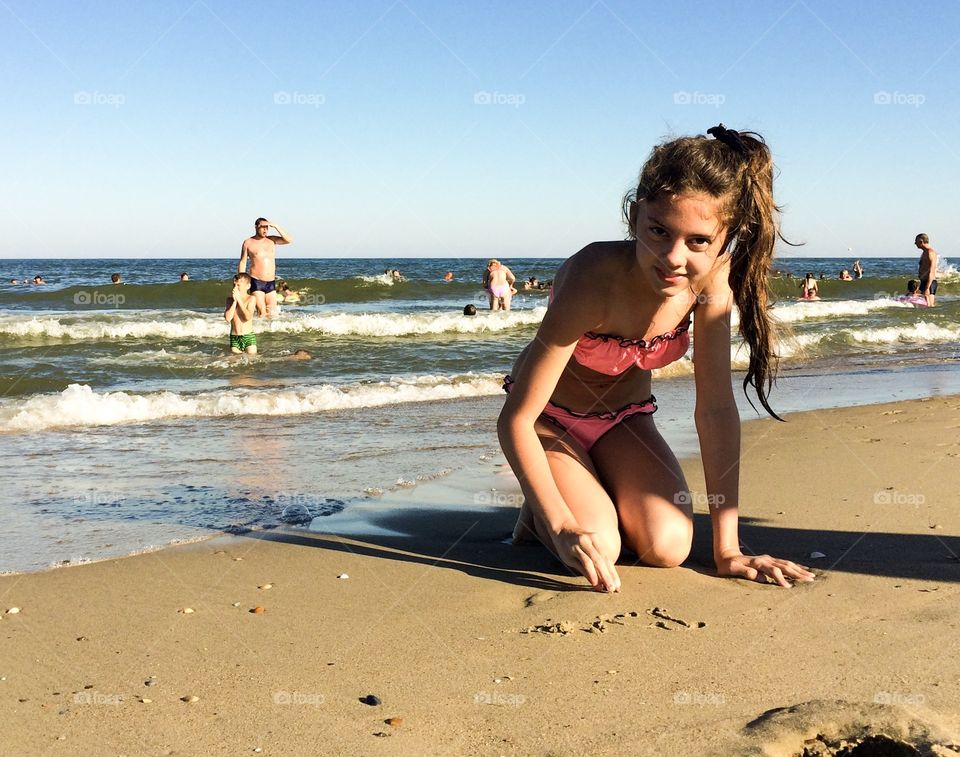 Girl on a beach writing on a sand