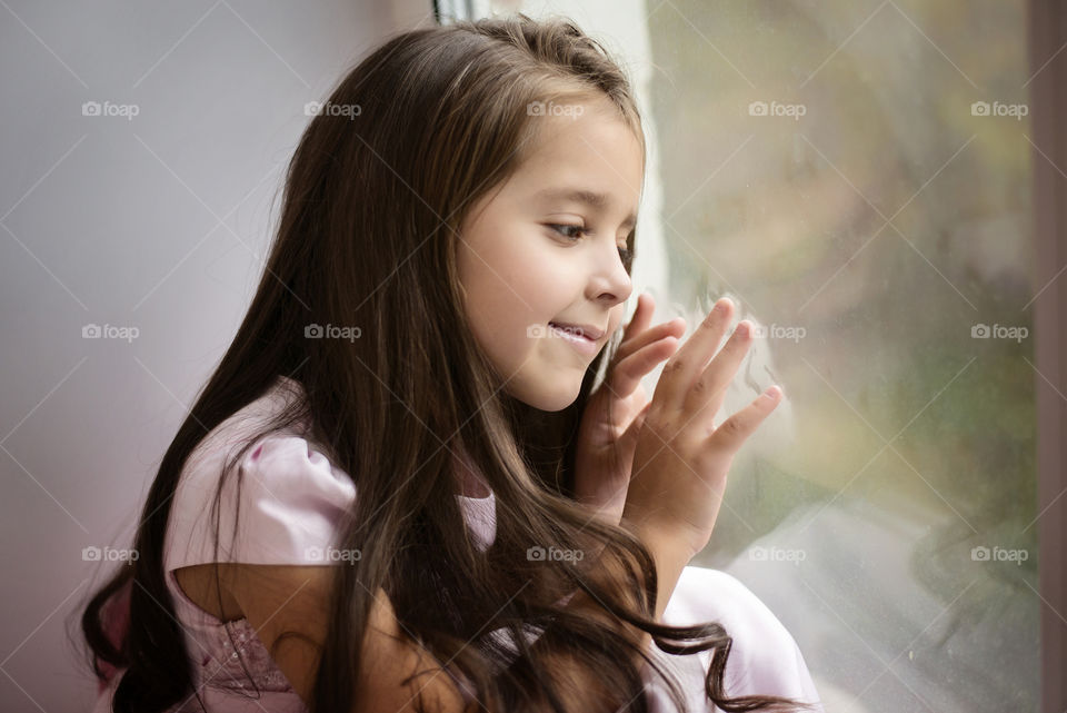 Little girl sitting near glass window