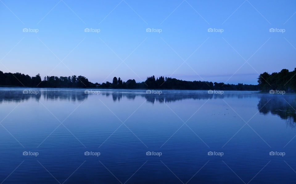 Silhouette of trees reflecting on lake