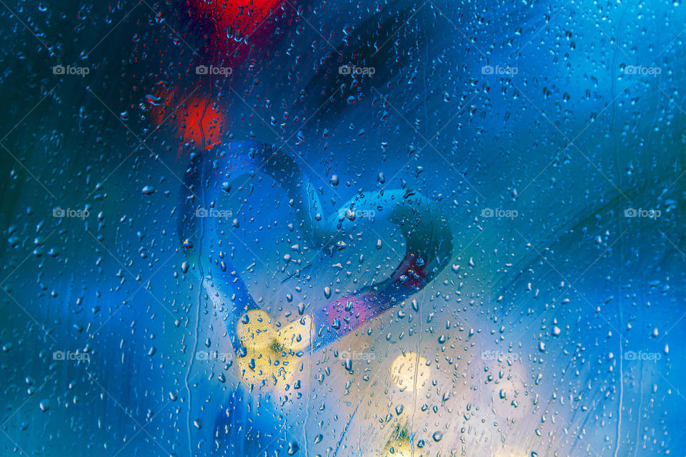 Heart in a rainy window with bokeh city lights at night
