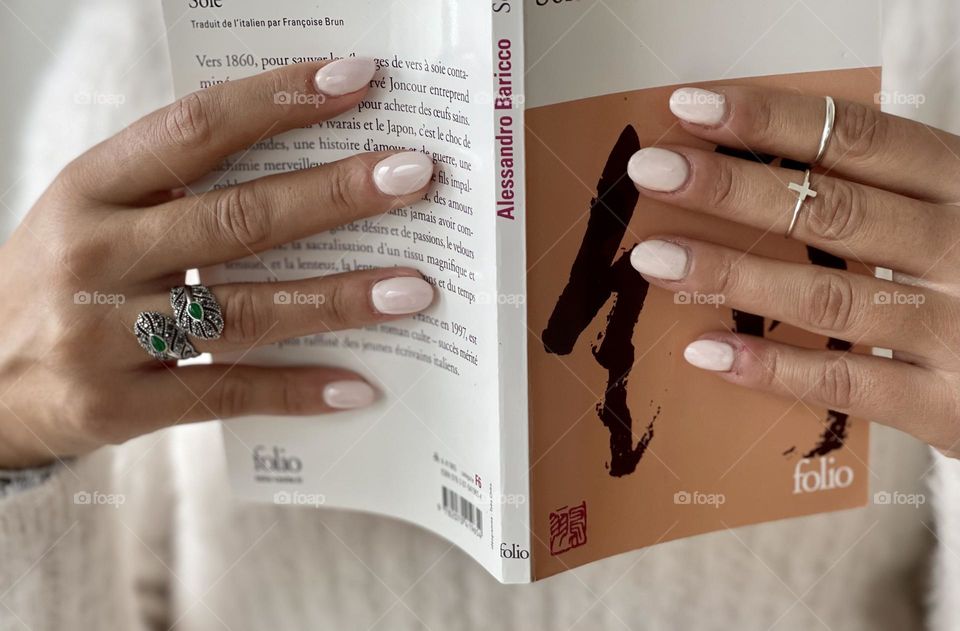 Woman hands wearing silver rings holding a book, woman reading a book 