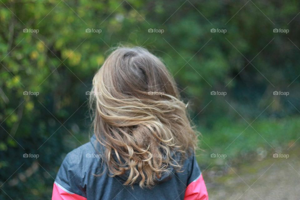 Flowing hair of a little girl walking in the forest
