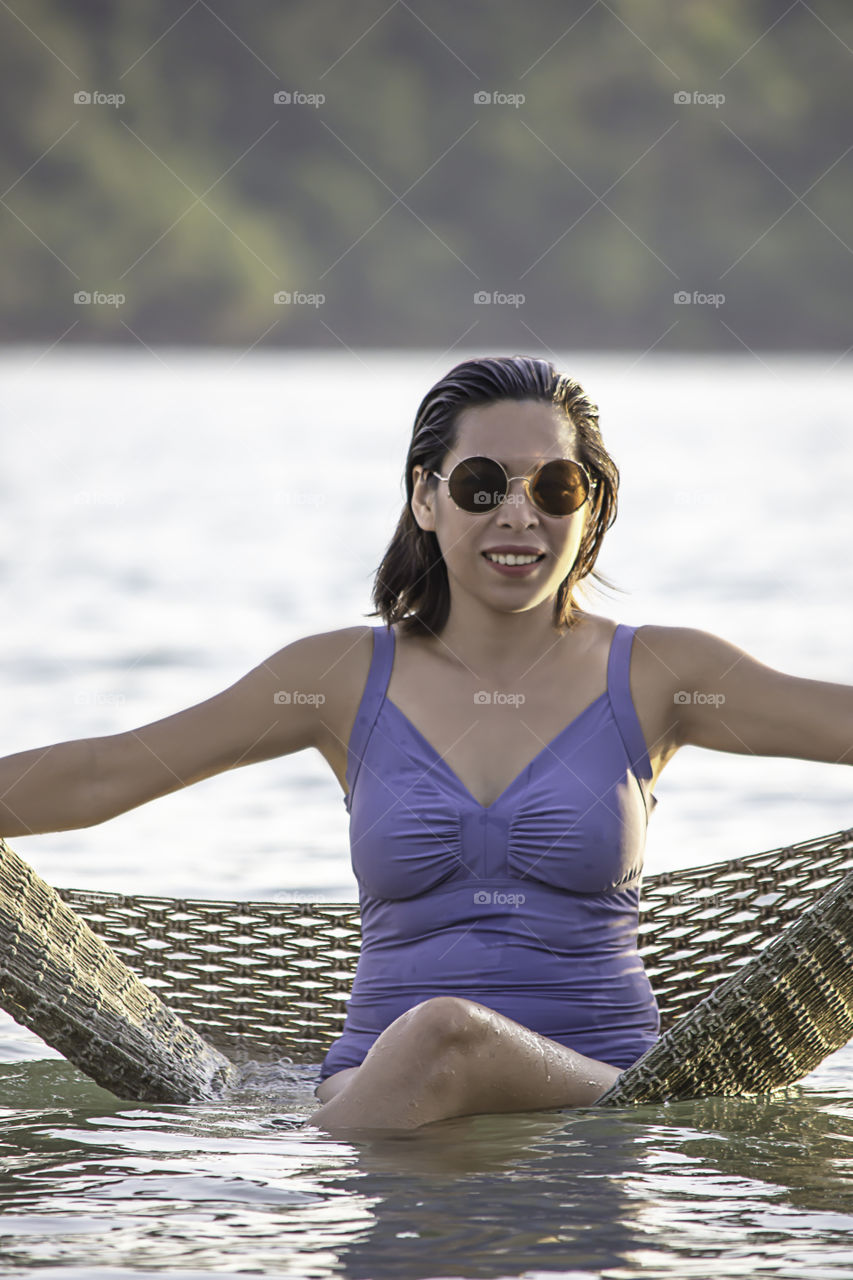 Portrait of Asian woman wearing a swimsuit on Hammock swing in sea.