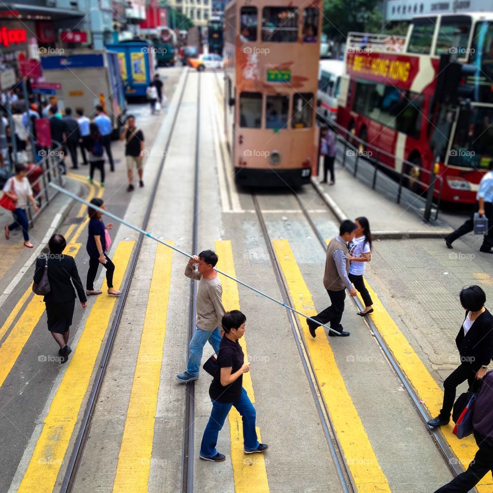 Busy crossing in Hong Kong - a photo taken from the top of Hong Kong's famous tram. Blue and white collar workers crossing the street.

