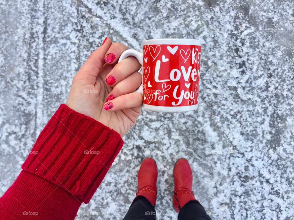 Woman wearing red pullover holding cup with love message in winter