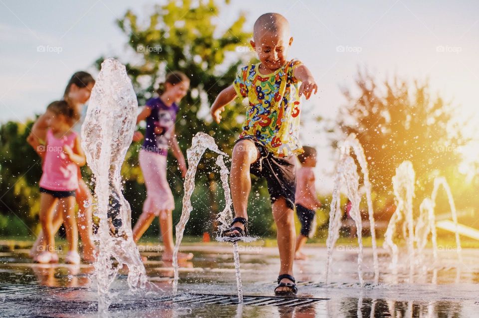 Kid having fun with water splashes during summer