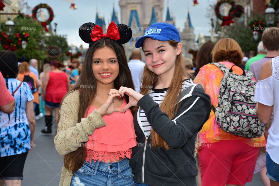 Two female friends making heart shape with hands