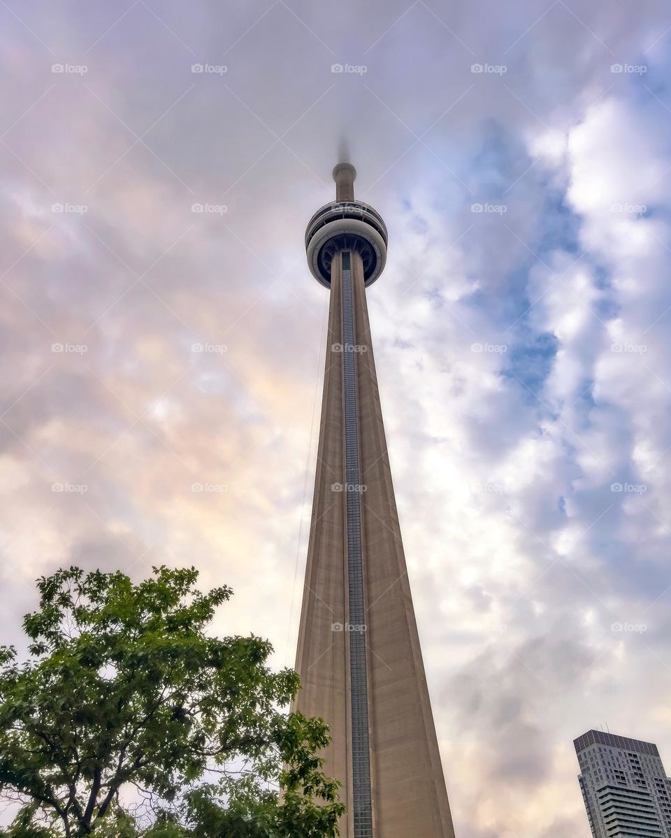 Toronto’s tall CN Tower landmark spire reaching into the clouds at sunset