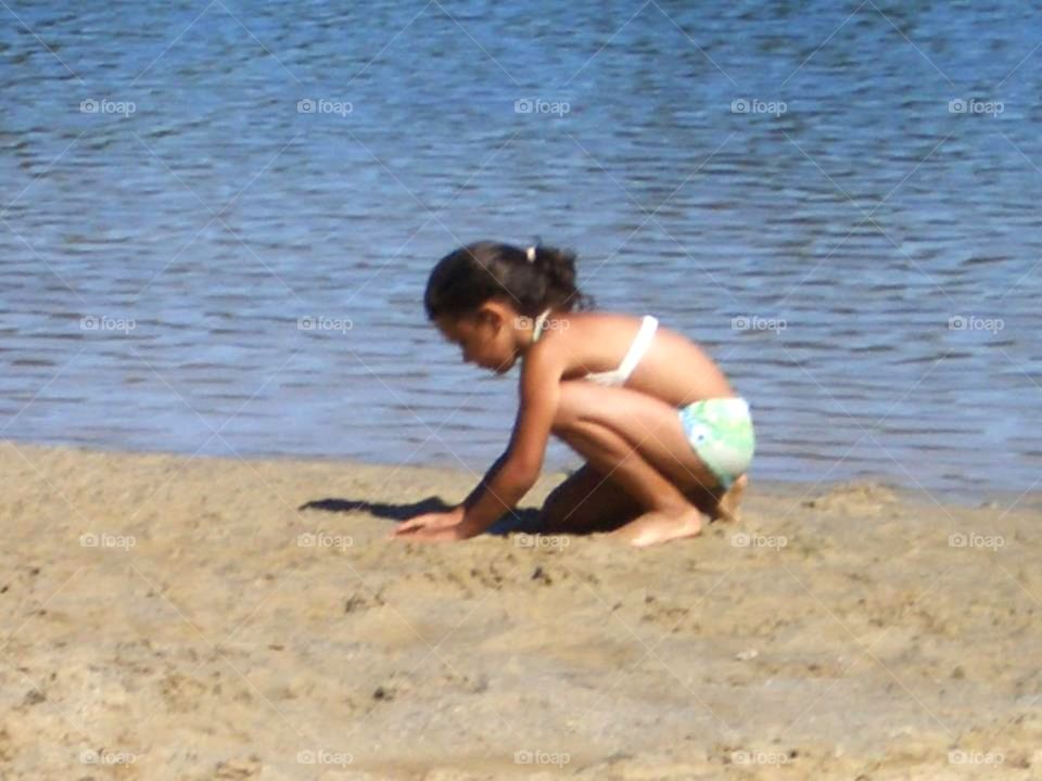 Little Girl Playing in the Sand on the Beach
