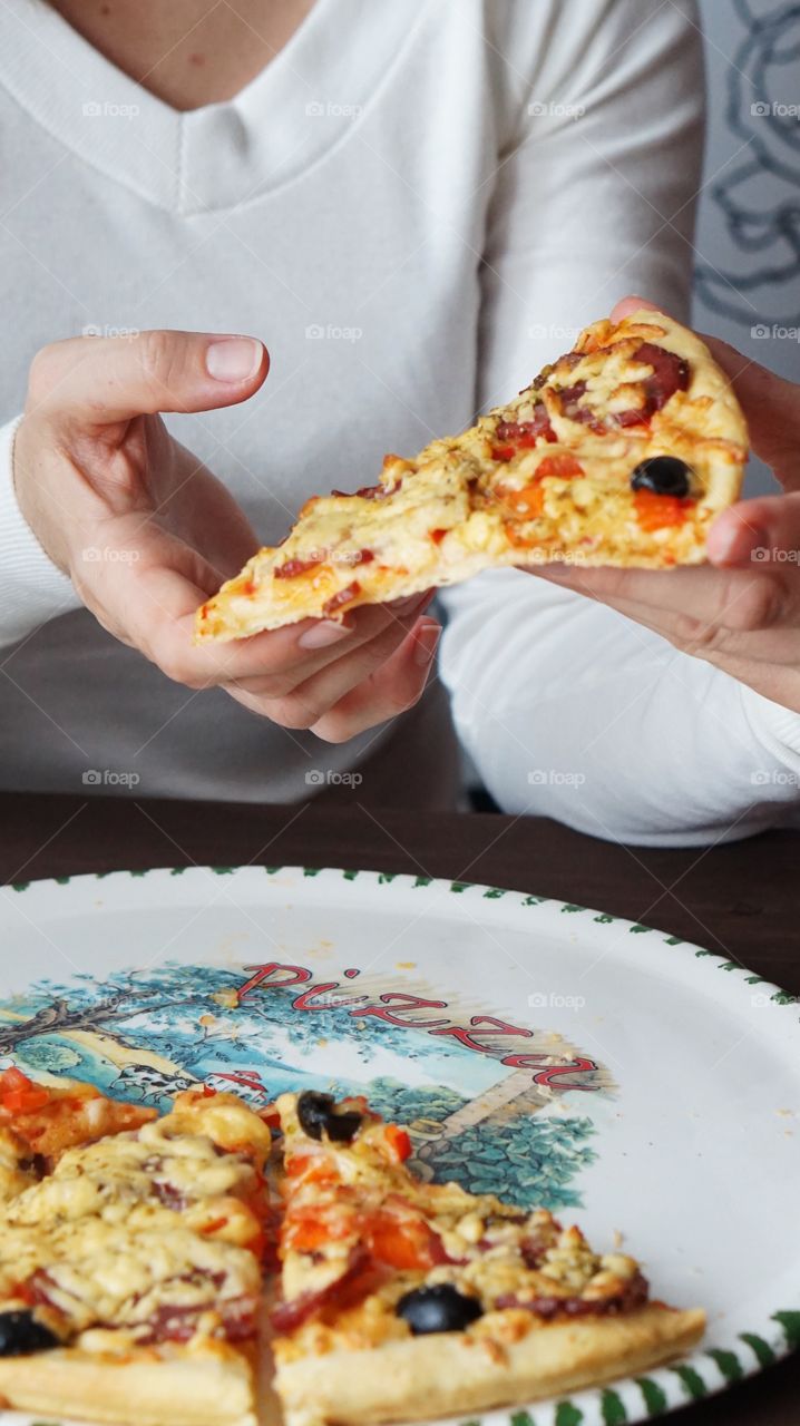 A woman holding slice of pizza