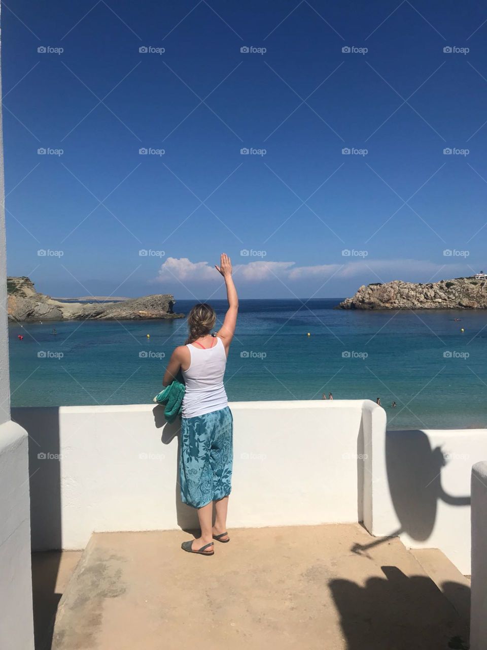 Women waves out to sea on a beautiful day in menorca 