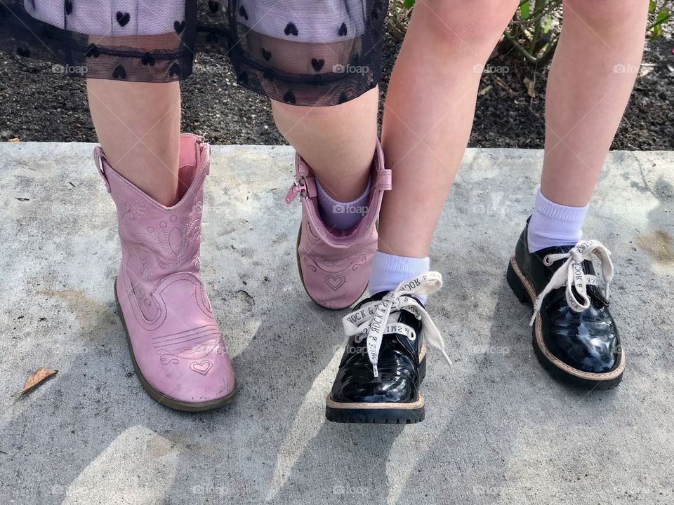 Little girls feet posing in pink boots and shiny black laced shoes