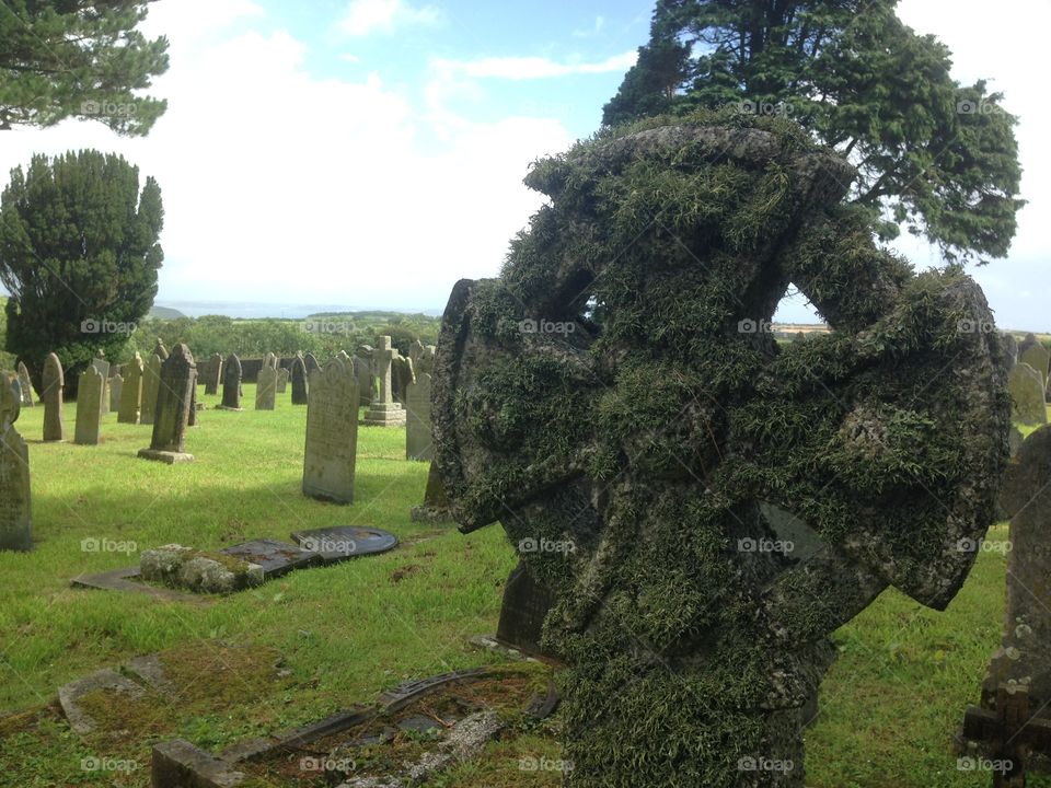 Grave jard, close up of a Celtic cross with a view over the hills of Cornwall.