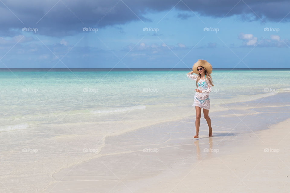 Happy woman running on the sandy beach 