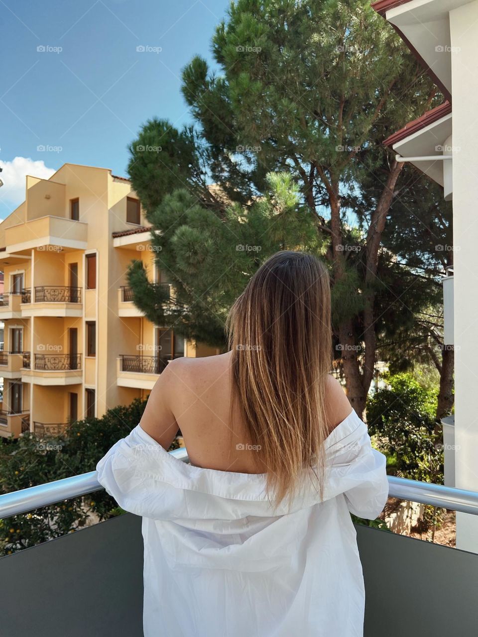 Woman in white shirt on a balcony with a view