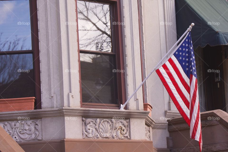 AMERICAN flag displayed on a window sill of old urban brownstone home