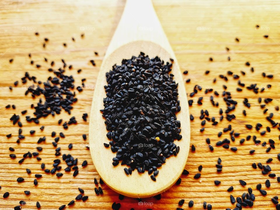 wooden ladle containing black cumin seeds