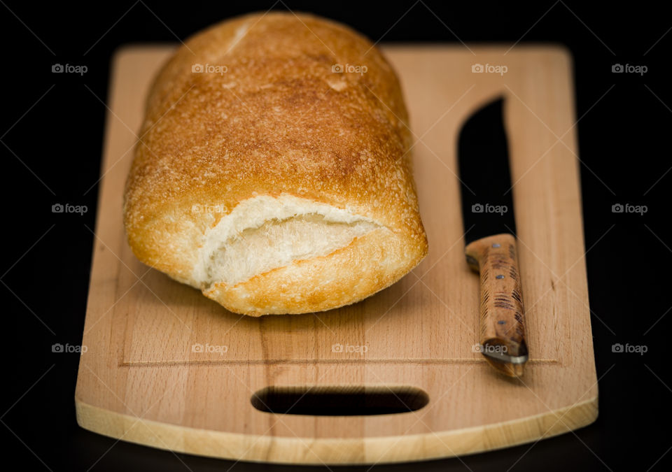freshly baked toasted, sliced ​​bread lies on a wooden cutting board next to a knife, on a black background