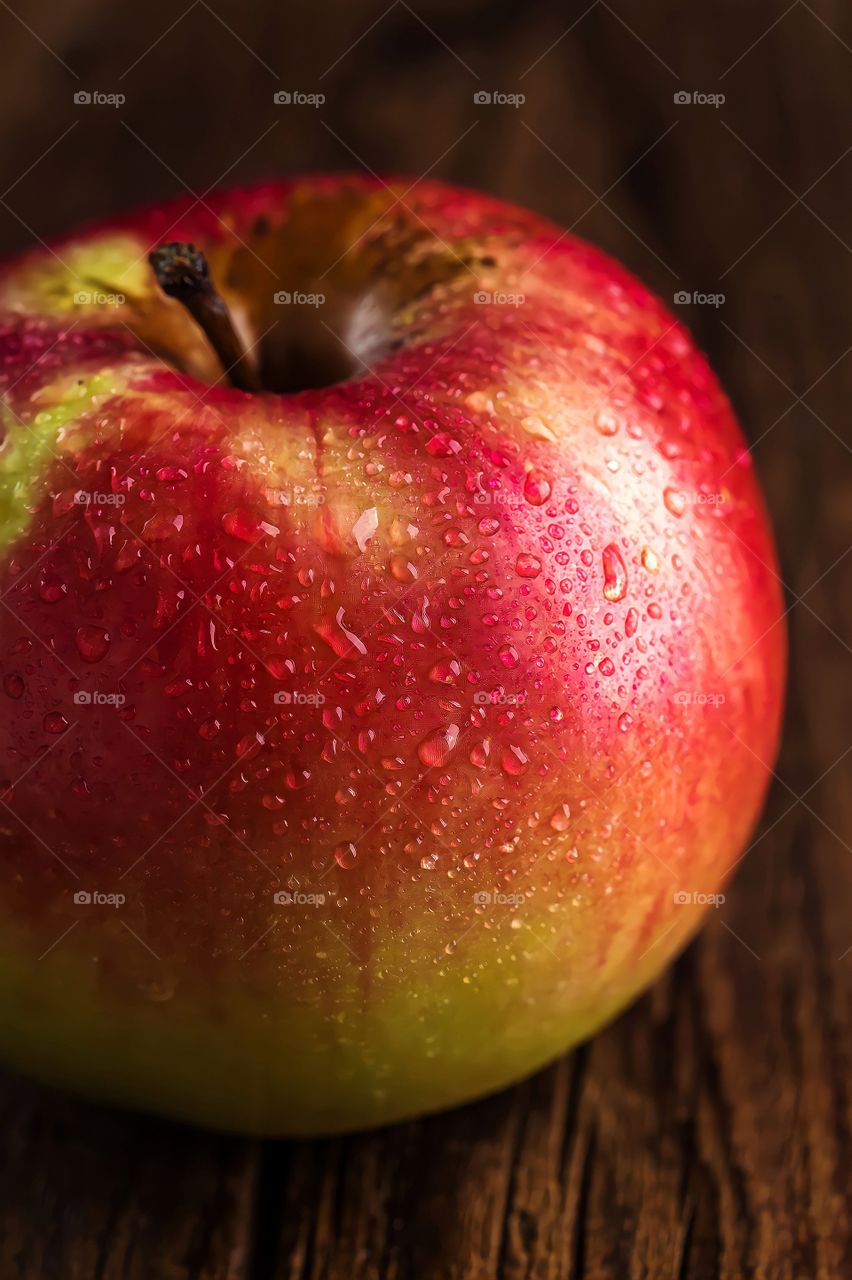 Red Apple on table
Close up of a red apple with dew droplets on wooden table.