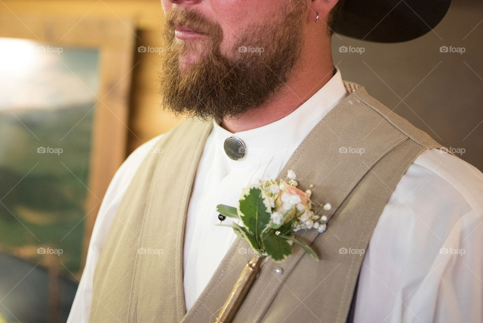 Groom getting ready for his wedding with hipster beard and homemade bullet casing boutonnière 