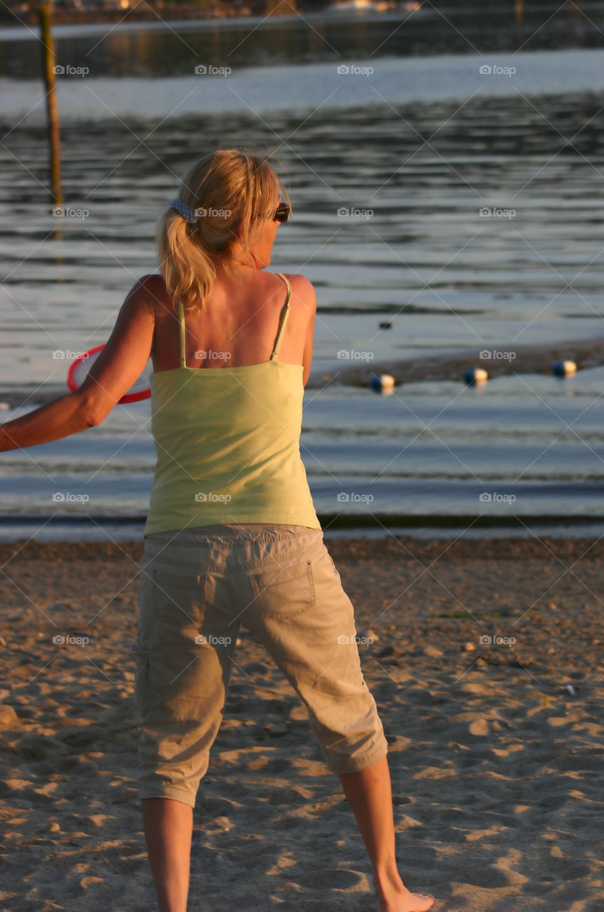Fun in the Golden glow. A fun game of frisbee at the beach just as the sun casts it's golden glow which is reflected on the woman
