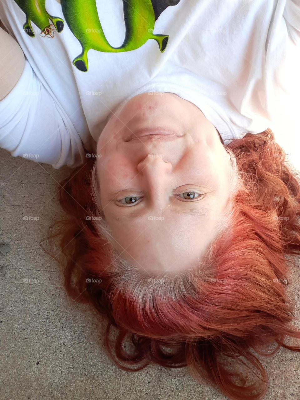 I like to sit and lay on my balcony to get some fresh air. I have mostly auburn hair and I am wearing a white shirt that says Ogre Achievers on it.