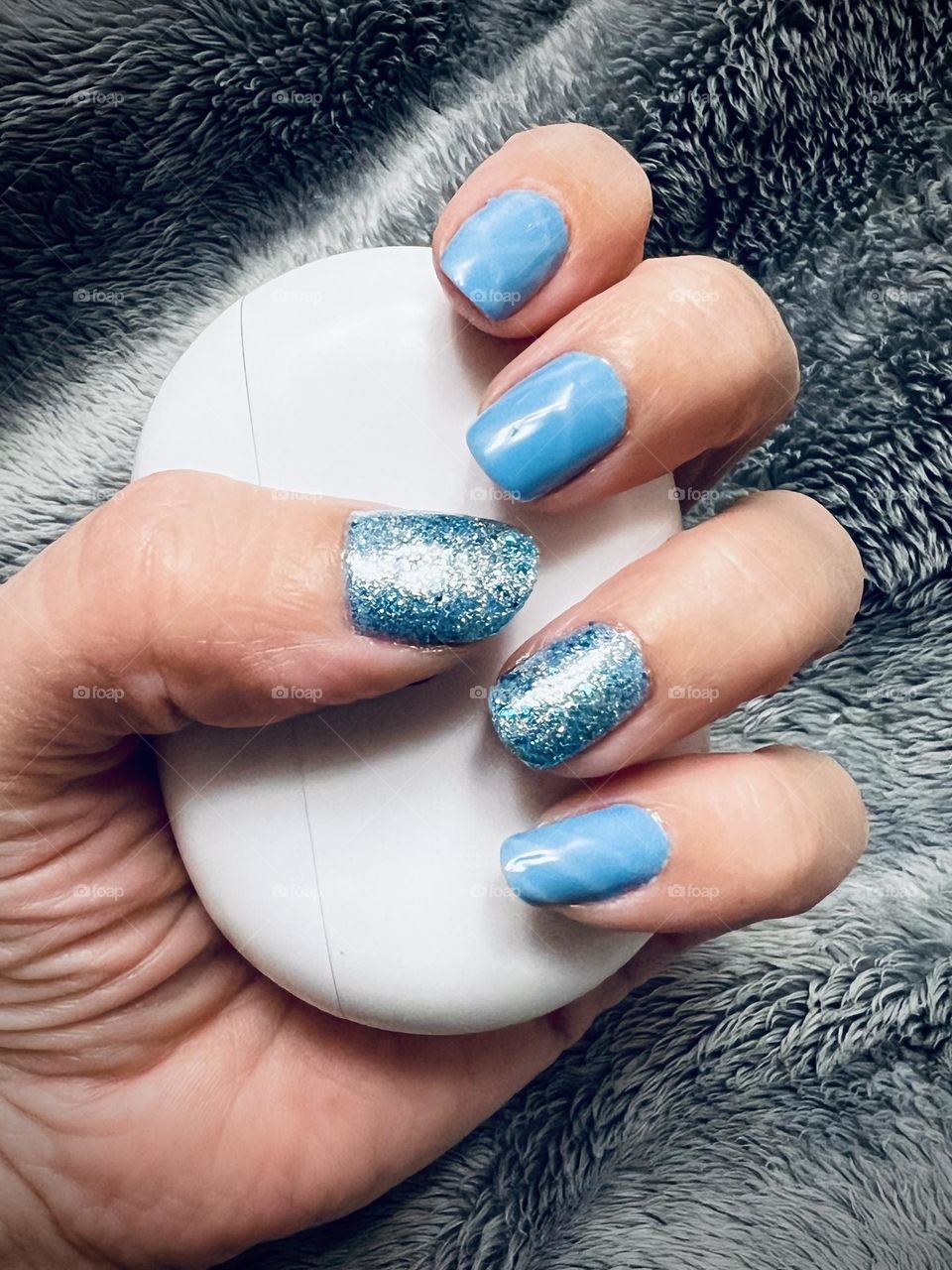 Soft glittery blue gel manicure holding beats earbuds