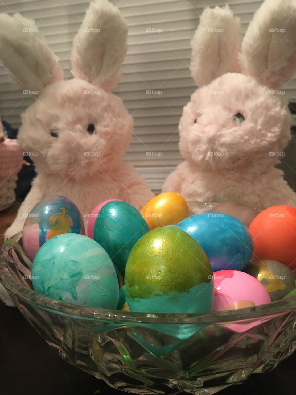 Pass Golden Shimmer Easter eggs in Tiffany glass bowl with two stuffed pink bunnies 