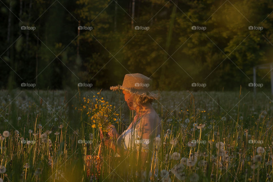 woman collects flowers at sunset