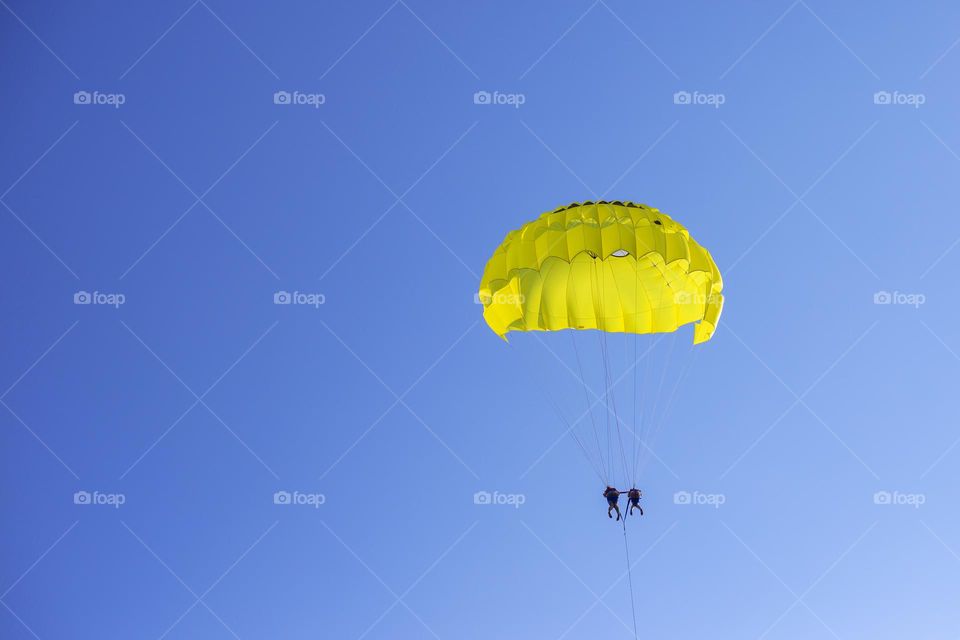 Yellow parachute with people in the blue sky 