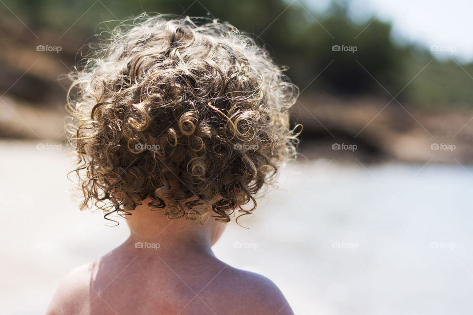 curly hair baby on beach. curly baby boy playing on beach