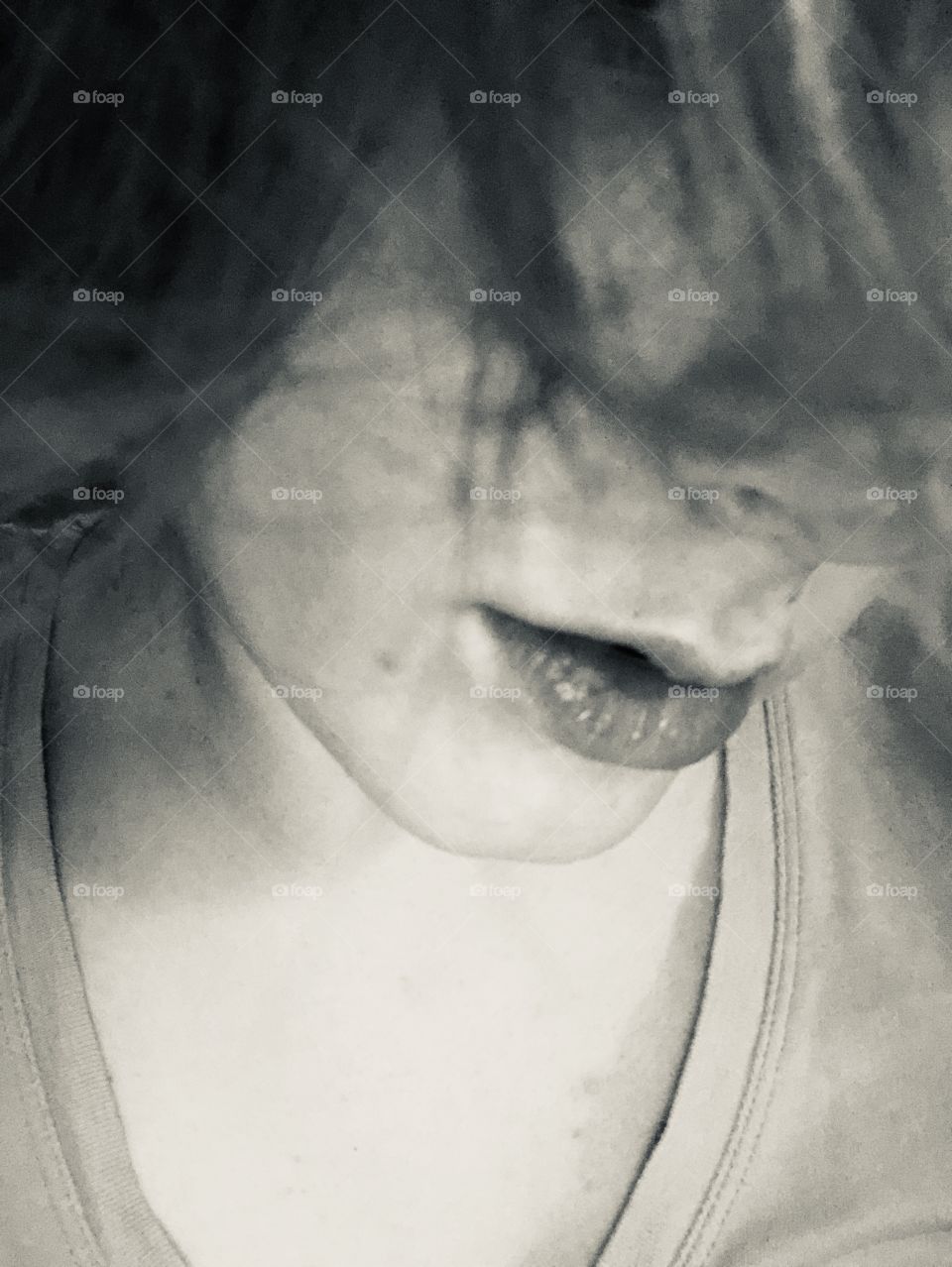 A young woman’s soft lips glisten in the light. Monochrome.