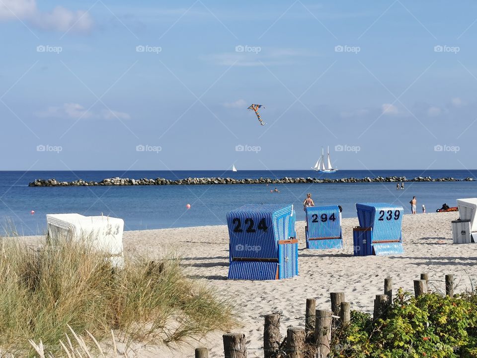 Strandkörbe mit Blick auf ein Segelschiff