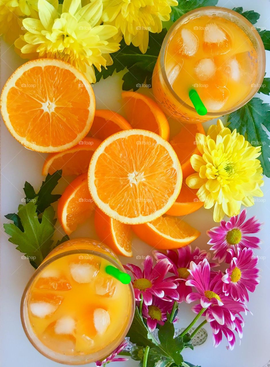 Summer treats flat lay: fresh orange juice and  wedges with fresh blooms of chrysanthemum and daisies