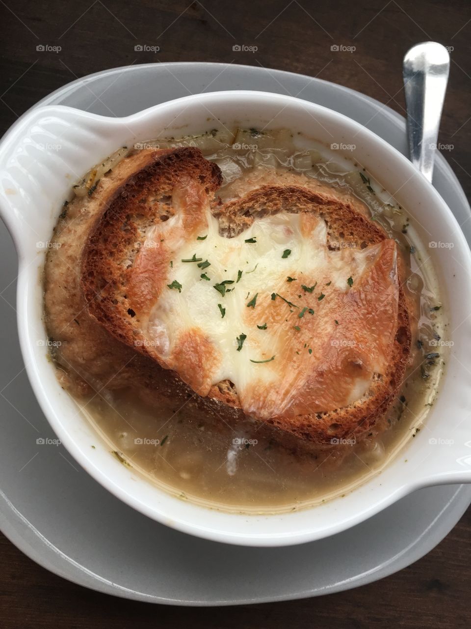 Home made French onion soup in our new soup bowls. Great autumn and winter dish. Hearty and delicious. The crouton is made out of day old bakery bread. The secret ingredient flavour you would never guess is Italian seasoning.  Great wood background. 