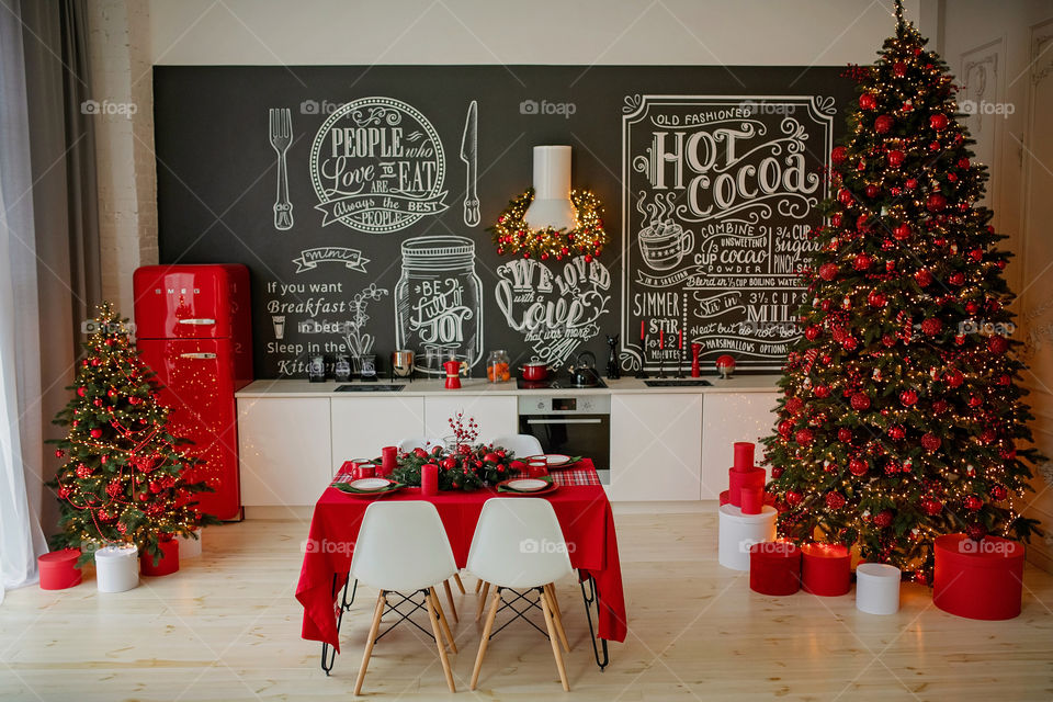 Festive winter cozy kitchen interior with garlands, decorations and gifts.  Christmas dinner at the decorated table.