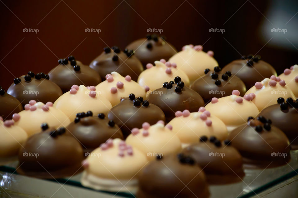 Beautiful gourmet dark chocolate, milk chocolate and white chocolate decorated luxury cacao round confections on tray selective focus dessert food photography background 