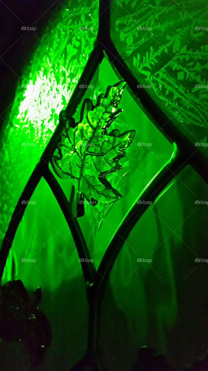 Green Porch Light shining through glass front door with leaf shaped gel clings.