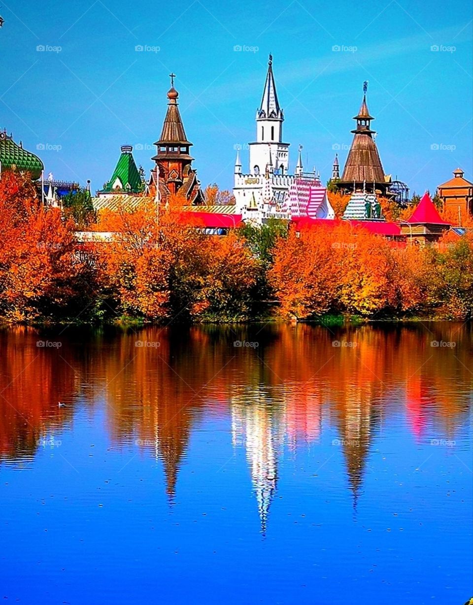 Contrast of colors in nature: blue and orange. Sky and water are blue, autumn trees are orange. Scenery