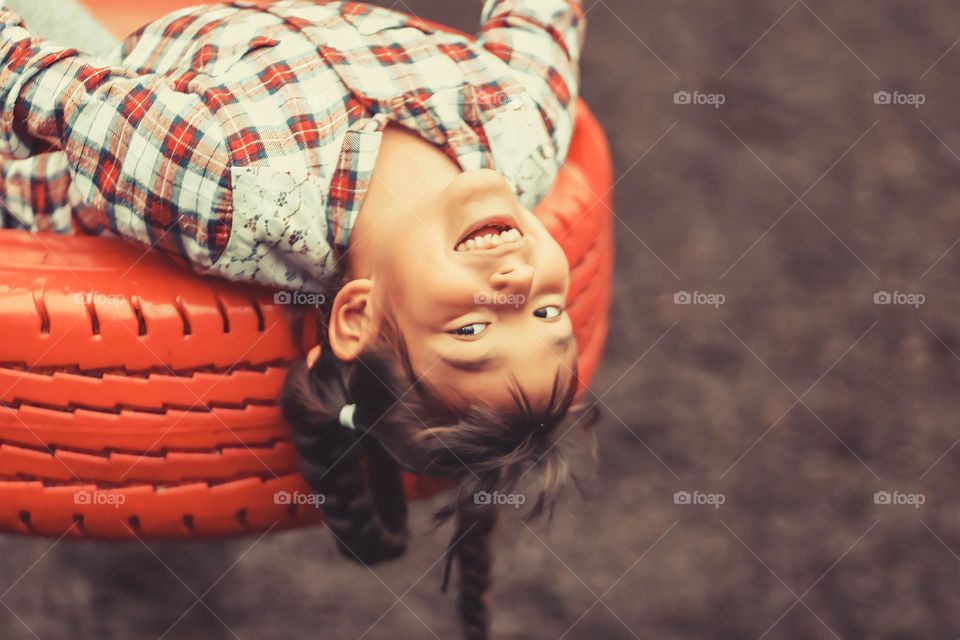 Cute little girl upside-down on a swing