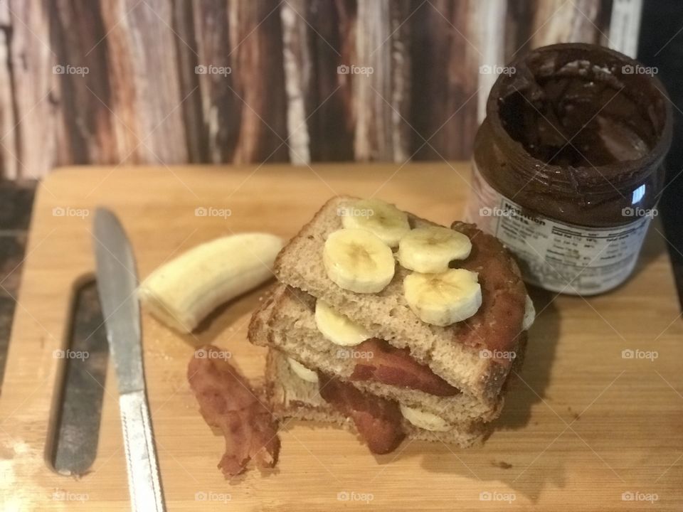 A delicious display of a Nutella, bacon and banana sandwich on a cutting board against a wooden rustic background for lunch. USA, America