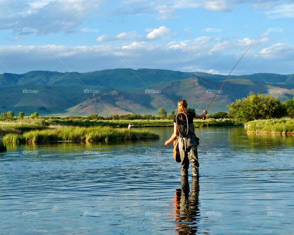 Woman fly fishing in Idaho’s Silver Creek, an iconic Western trout stream on a beautiful spring day. 