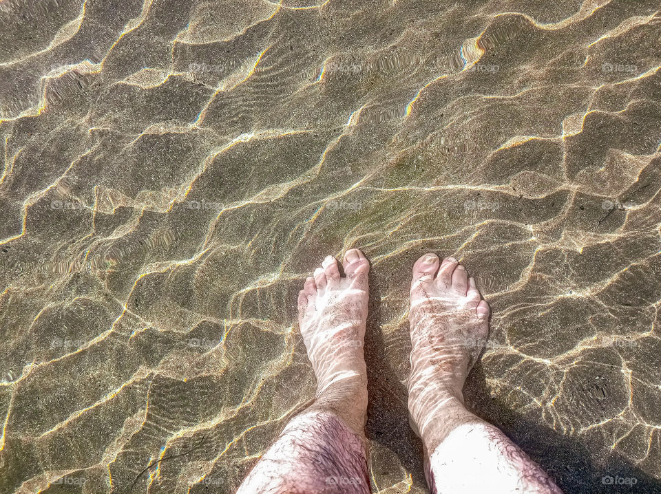 a man feet on the sand under water