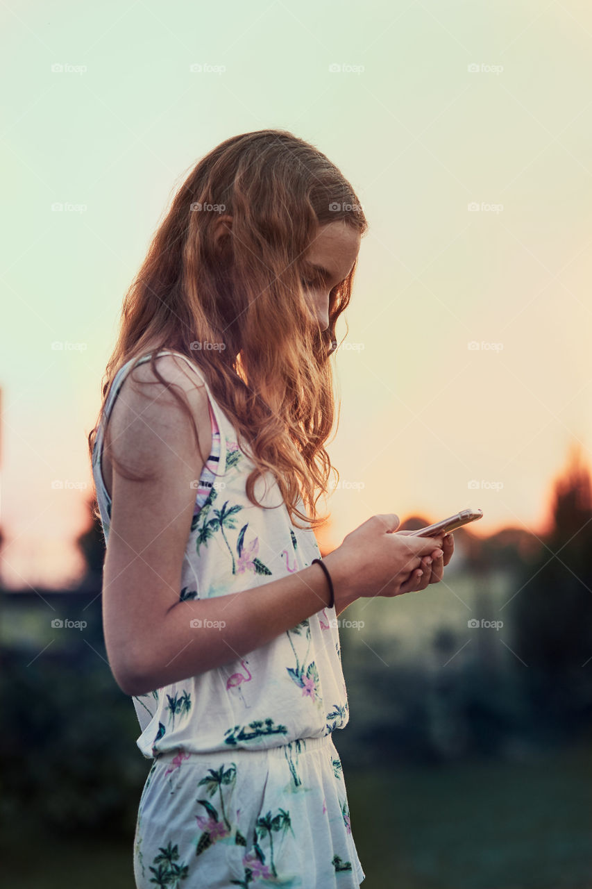 Young woman using mobile phone smartphone sitting on swing in a backyard. Candid people, real moments, authentic situations