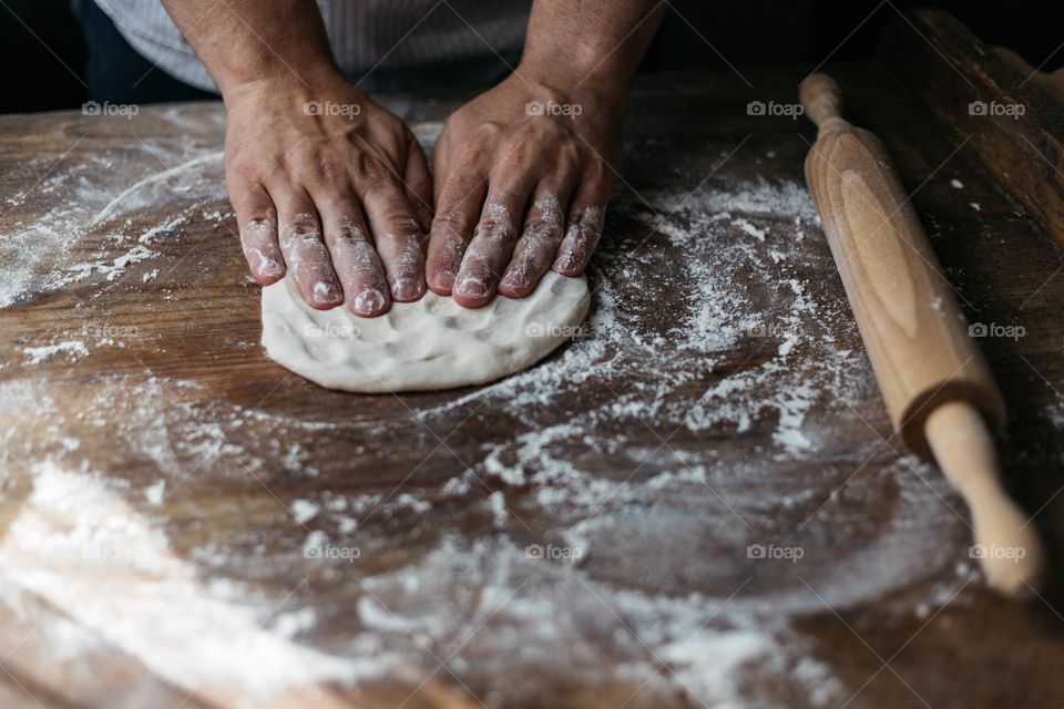 Man using his hands to knead the dough, for a homemade delicious bread.