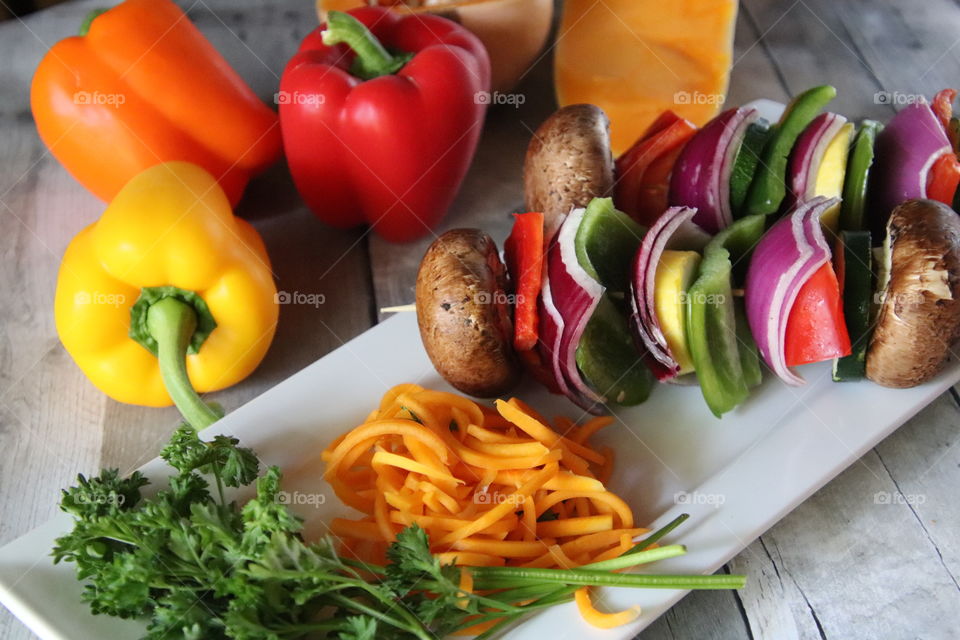 Healthy snack of colorful vegetables and herbs on white plate with wood background